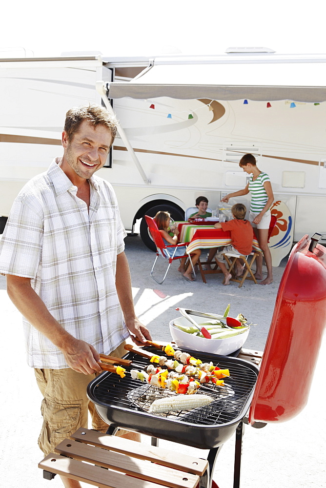 Man grilling dinner for family on beach