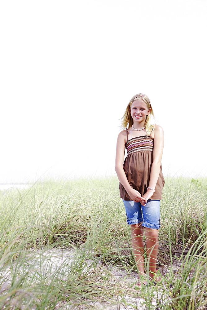 Girl standing on grassy sand dune