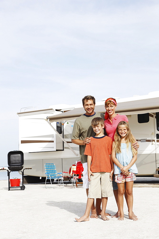 Family posing by motor home on beach