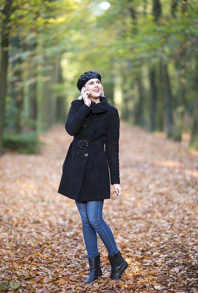 Smiling woman using phone while walking in forest, Goirle Netherlands