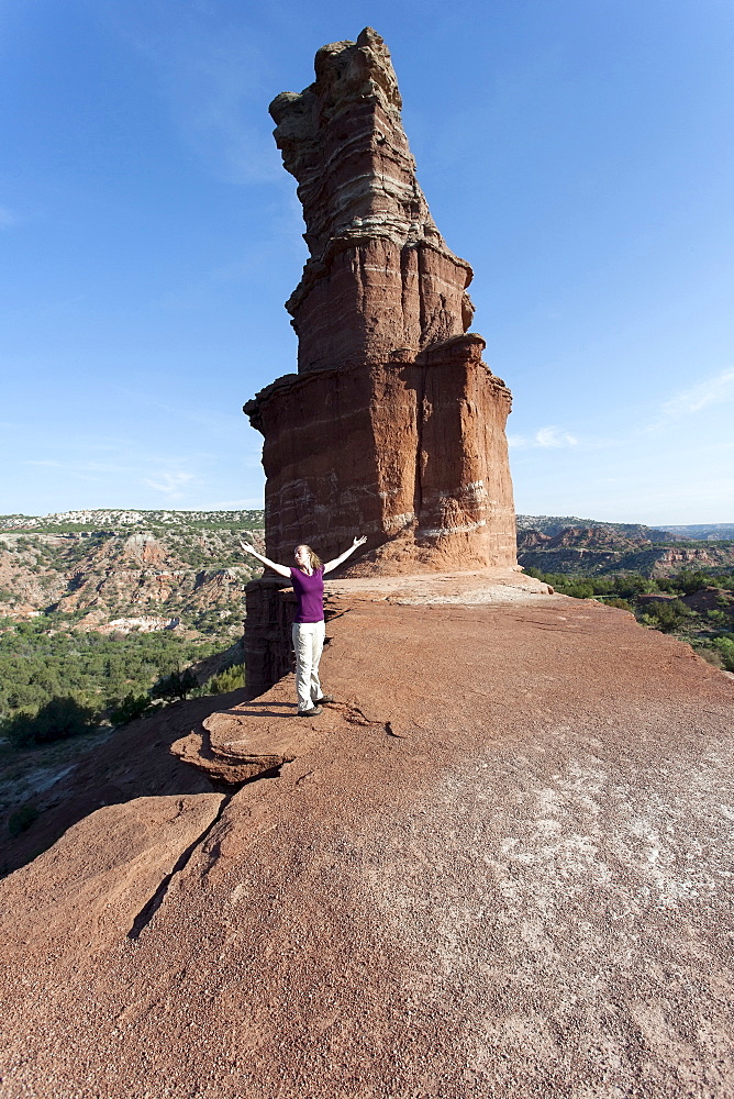 Woman with arms outstretched standing by rock formation, Palo Duro Canyon State Park Texas Travel U.S.A