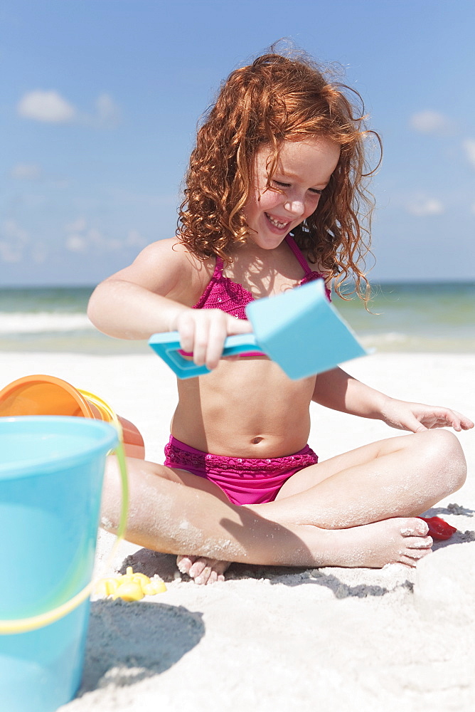 Girl digging in sand on beach