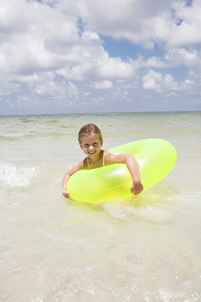 Girl playing in inflatable ring into ocean