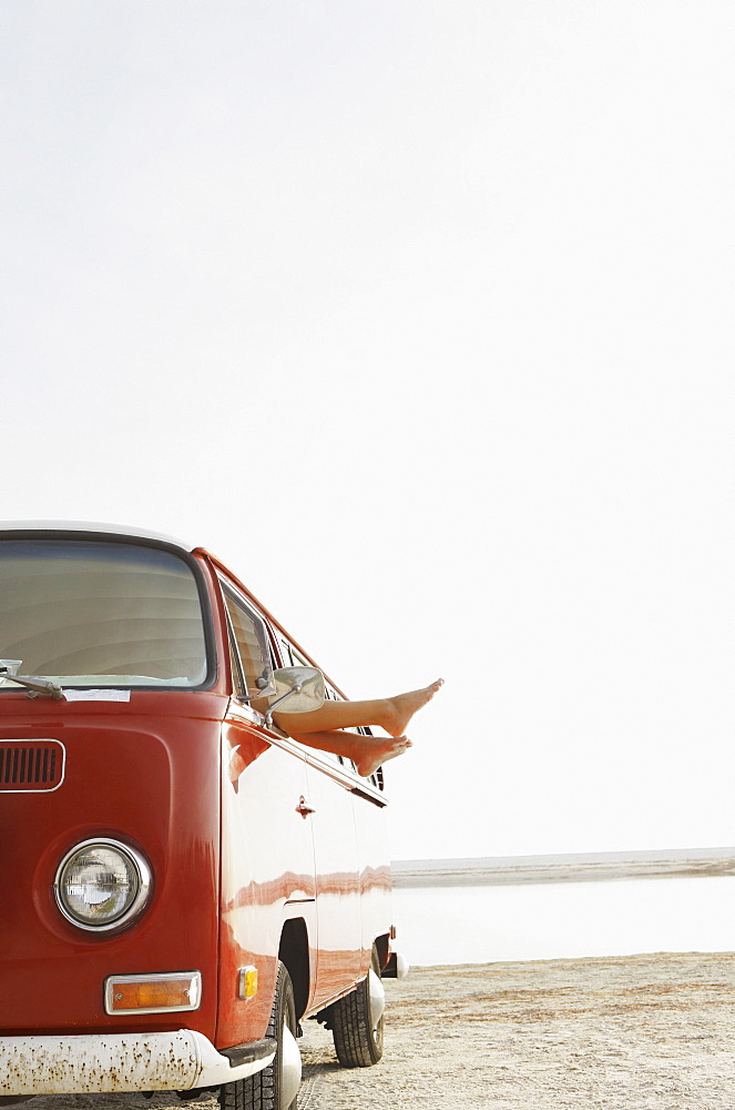 Feet sticking out of van window on beach