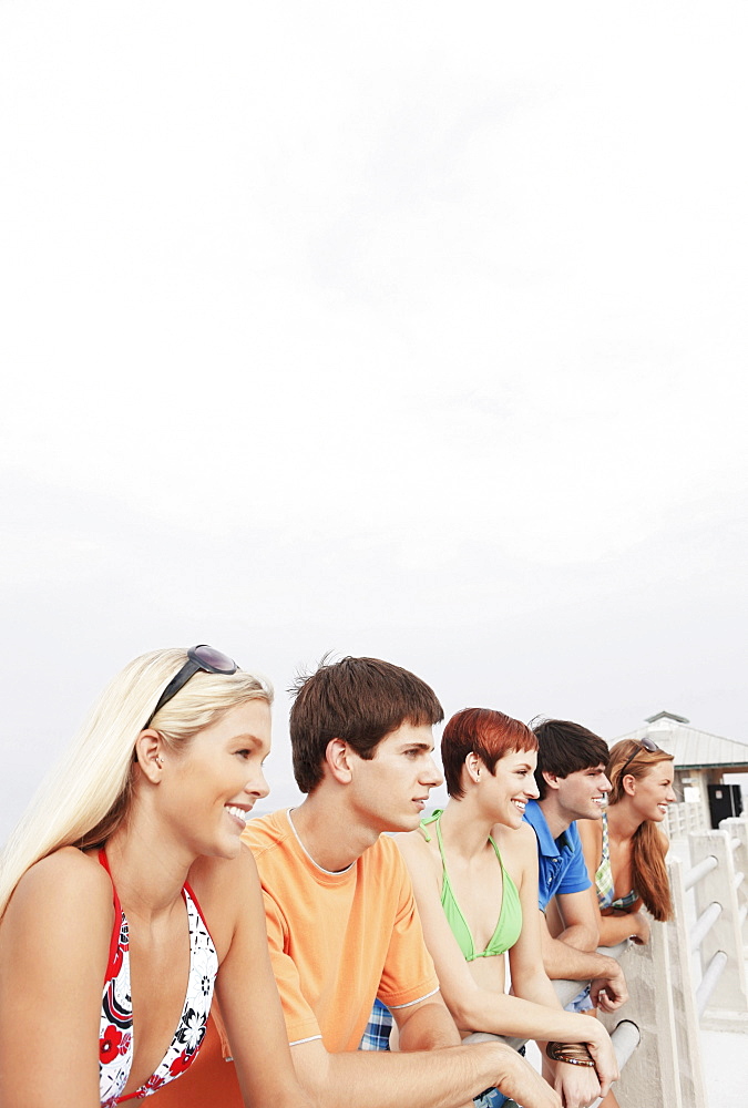 Friends posing on boardwalk railing