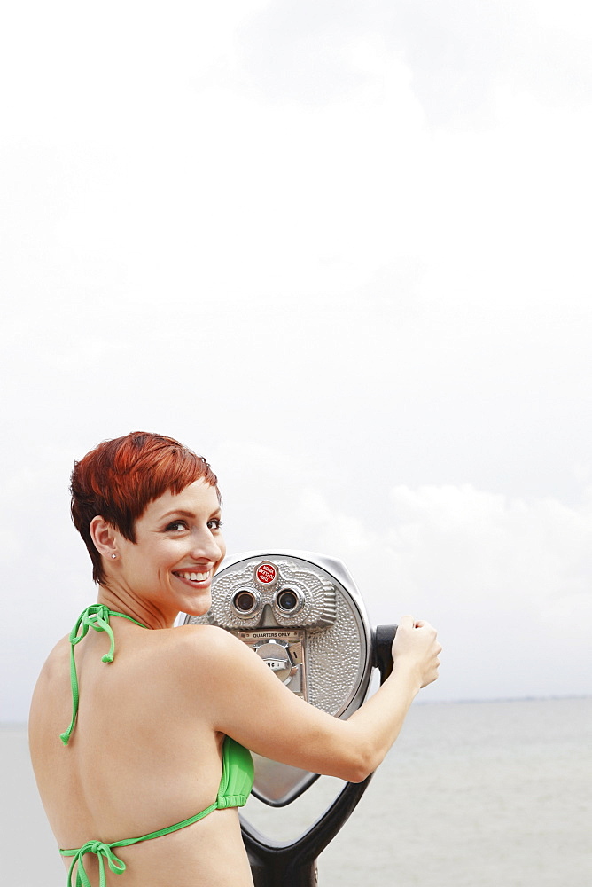 Woman looking through coin-operated binoculars