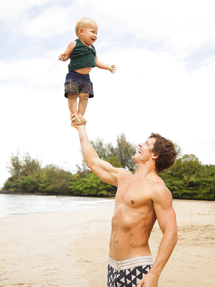 Father with son (6-11 months) on beach, Kauai, Hawaii