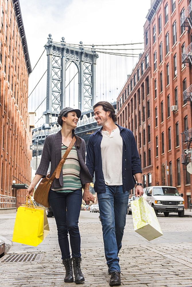 Couple walking on street, Brooklyn Bridge in background, Brooklyn, New York