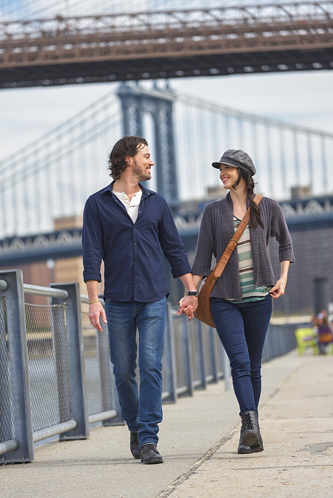 Couple walking on promenade, Brooklyn Bridge in background, Brooklyn, New York