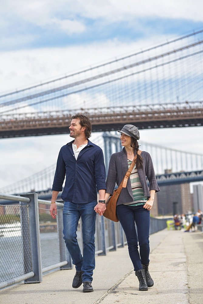 Couple walking on promenade, Brooklyn Bridge in background, Brooklyn, New York