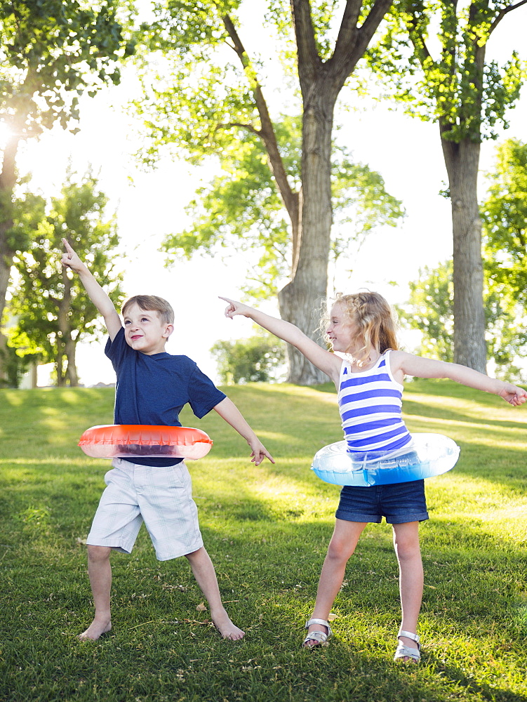 Two kids (4-5, 6-7) playing with inflatable rings in park, USA, Utah, Salt Lake City 