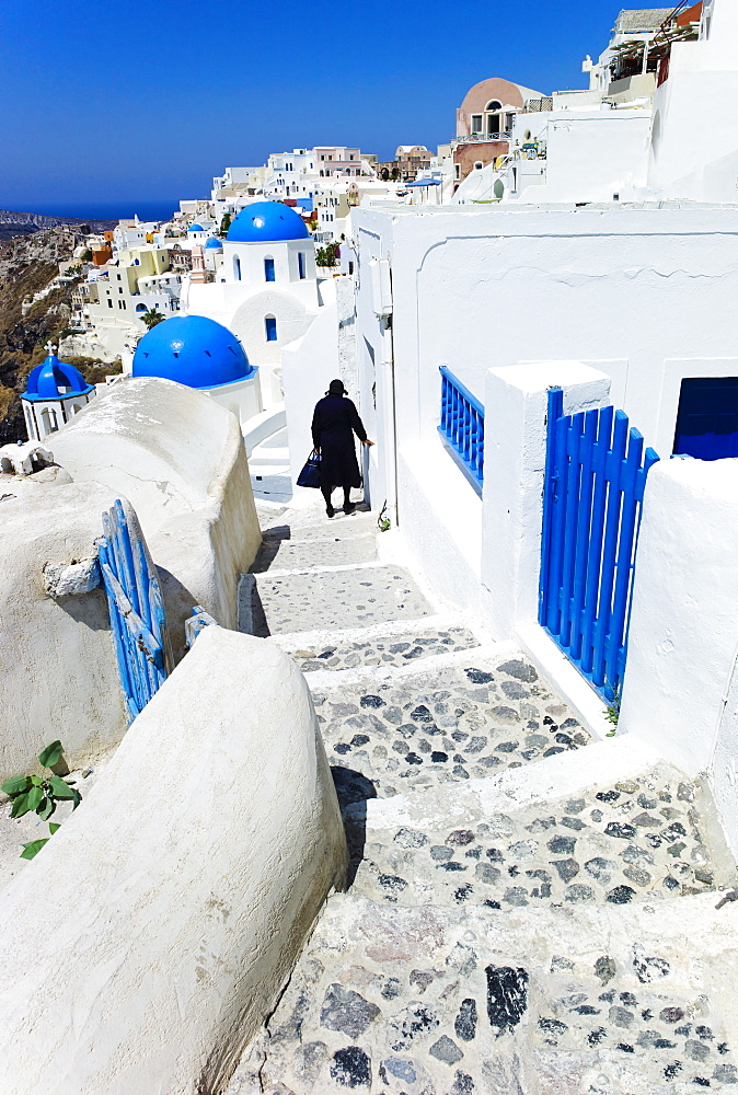 Greece, Cyclades Islands, Santorini, Oia, Woman walking down steps in town