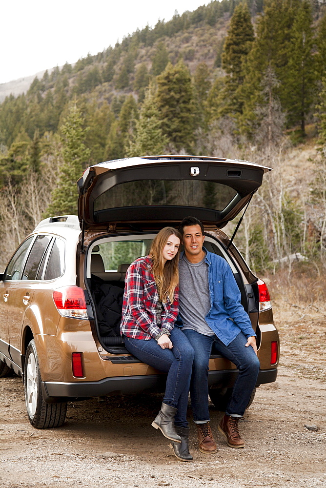 Portrait of young couple sitting in car trunk in non-urban scene, Salt Lake City, Utah