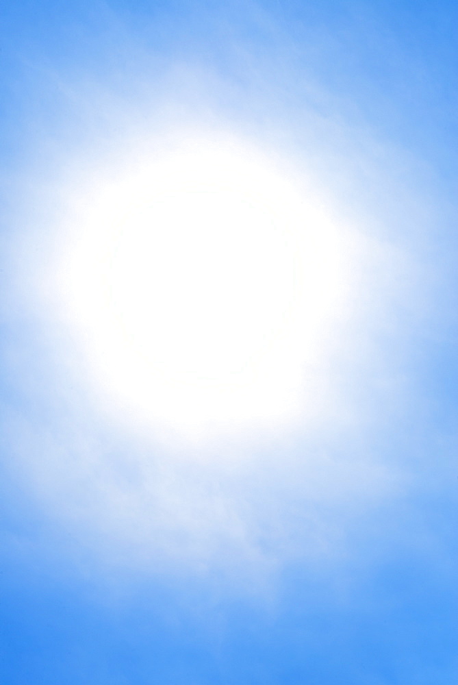 Sun behind small cloud on blue sky