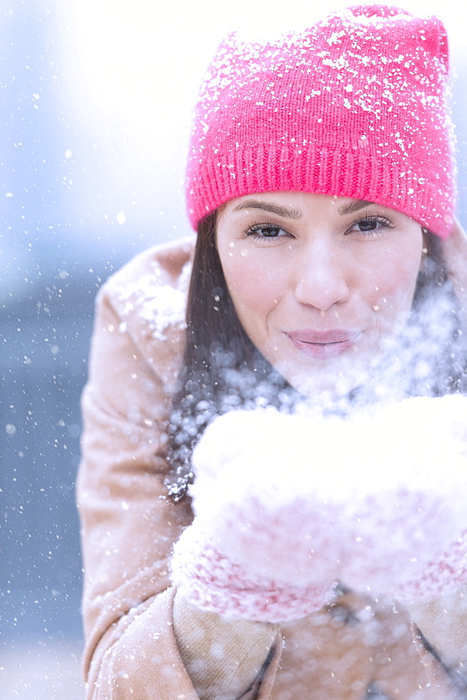 Portrait of woman blowing snow from hands