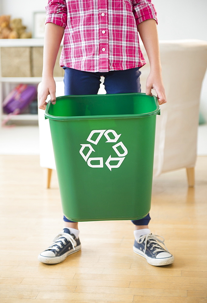 Close up of girl (8-9) holding recycle bin