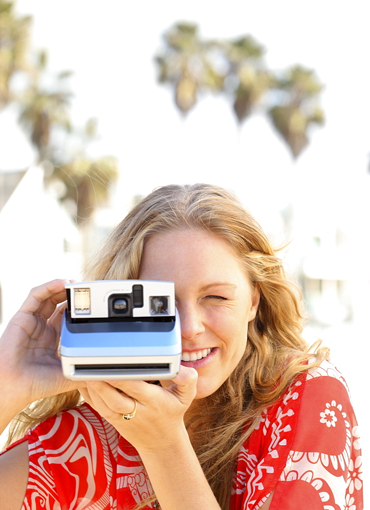 Woman taking photograph with instant camera
