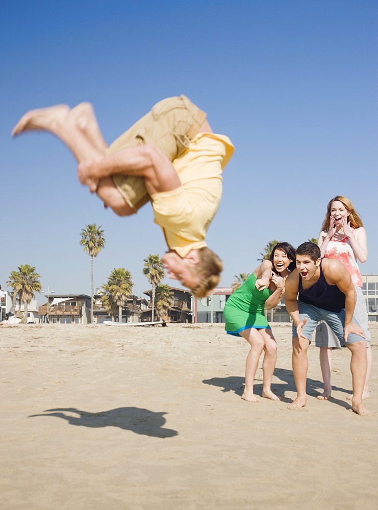 Man doing back flip on beach