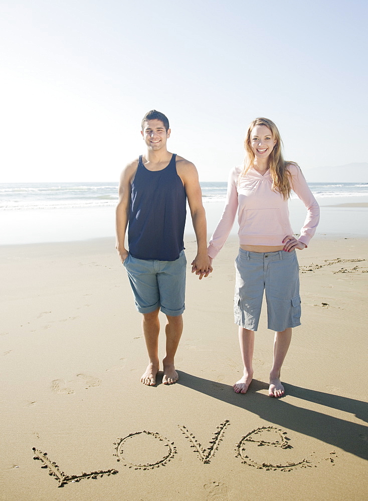 Couple next to Love written in sand