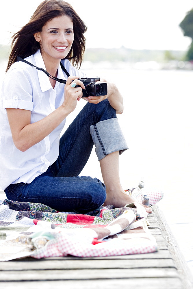 Woman with camera sitting on dock