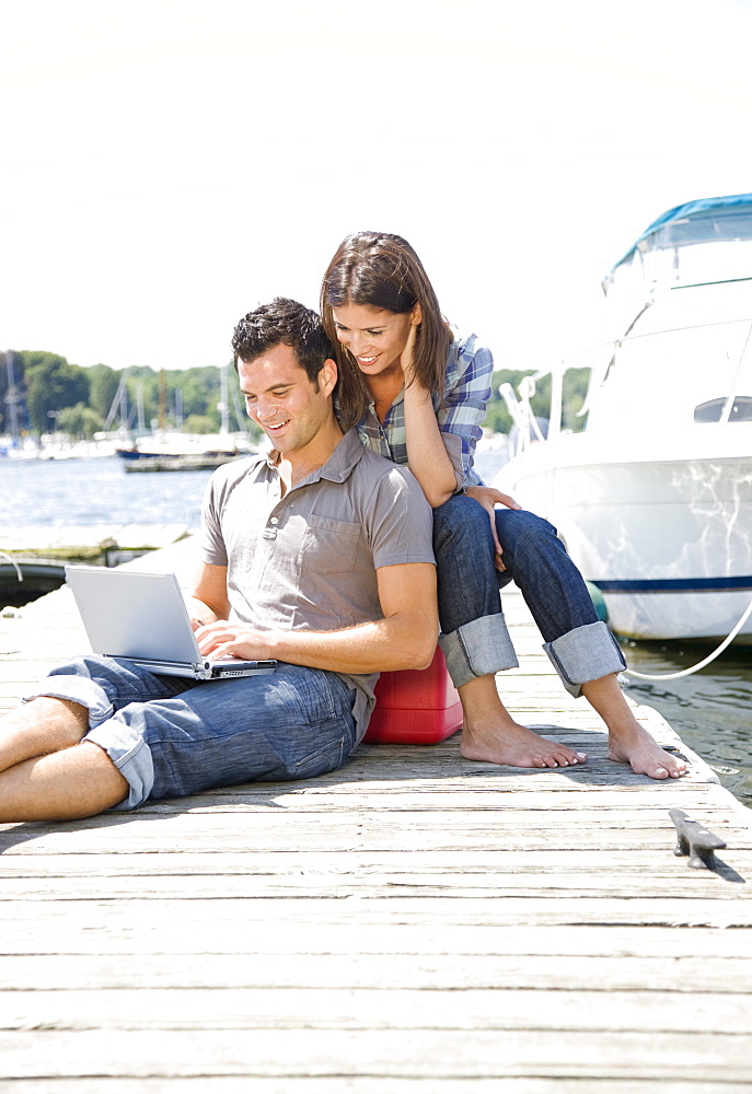 Couple using laptop on dock