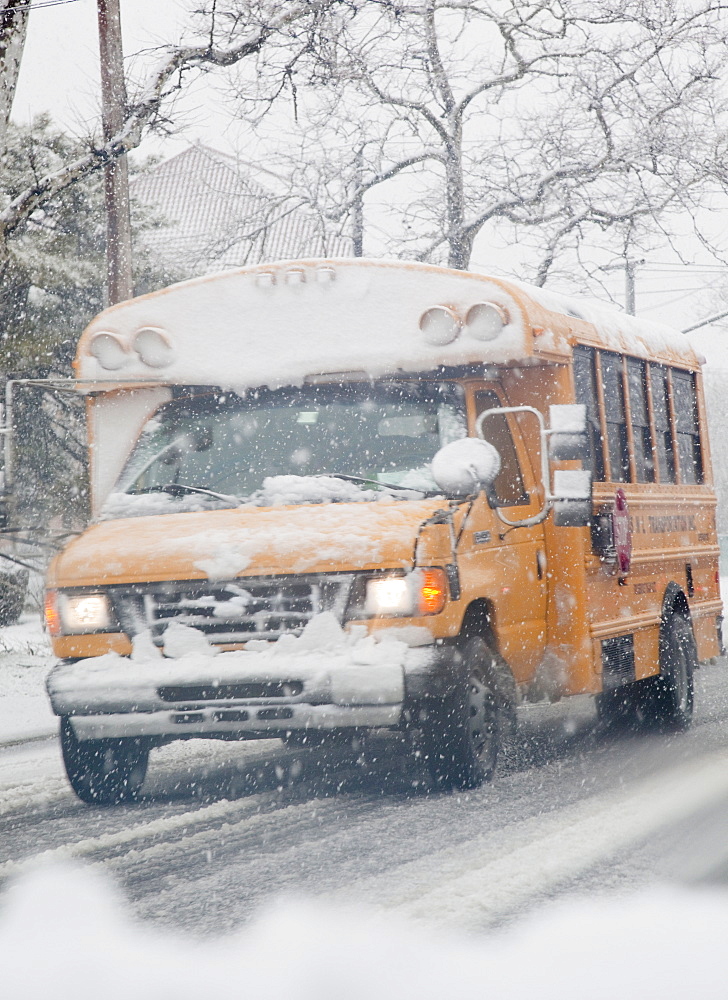 USA, New Jersey, Jersey City, school bus on road during blizzard