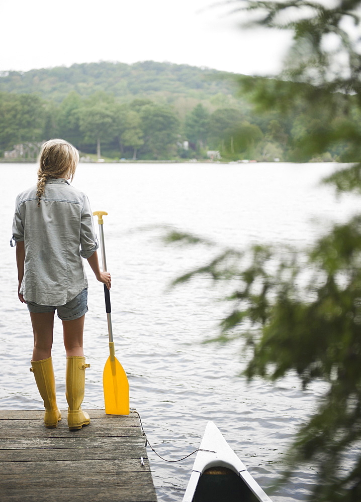 USA, New York, Putnam Valley, Roaring Brook Lake, Woman standing on pier with paddle