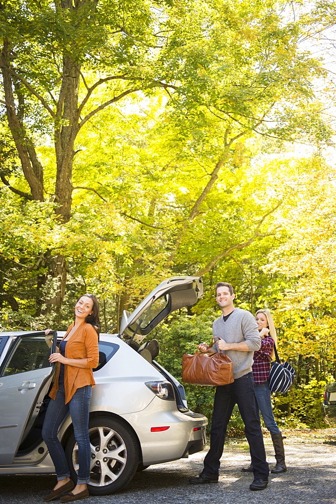 Three friends packing luggage into car, Newtown, Connecticut