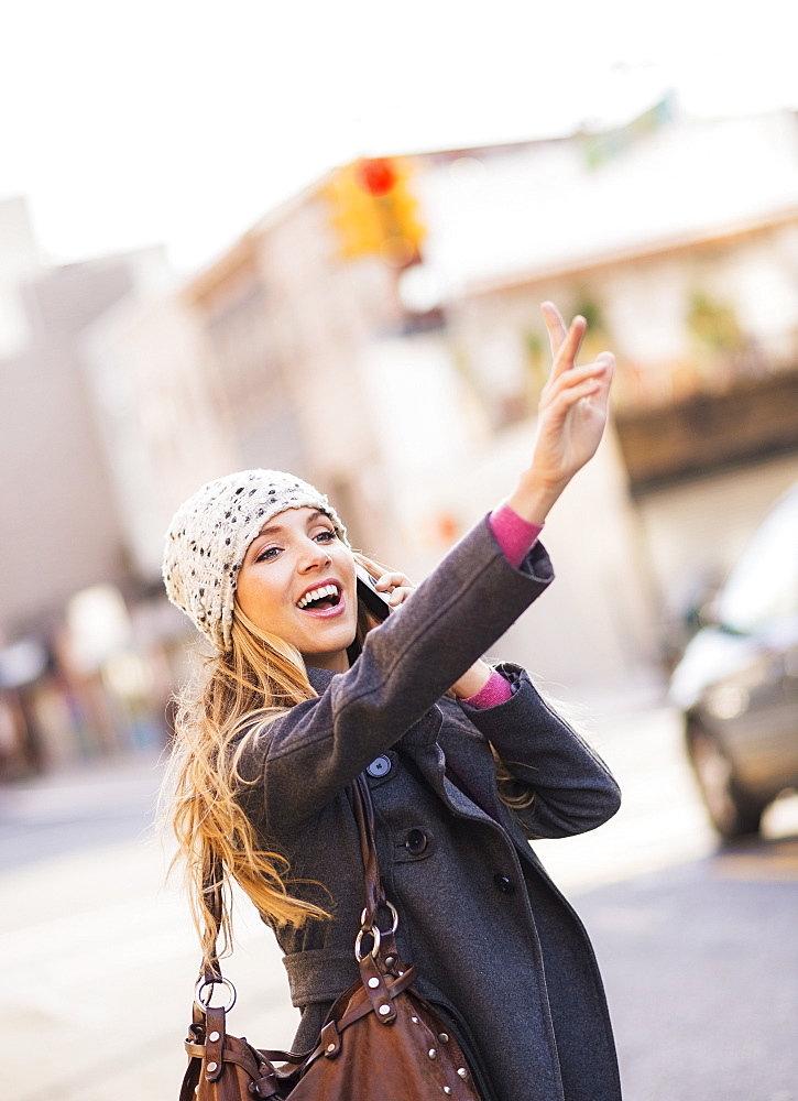 Portrait of blond woman hailing cab, USA, New York City, Brooklyn, Williamsburg