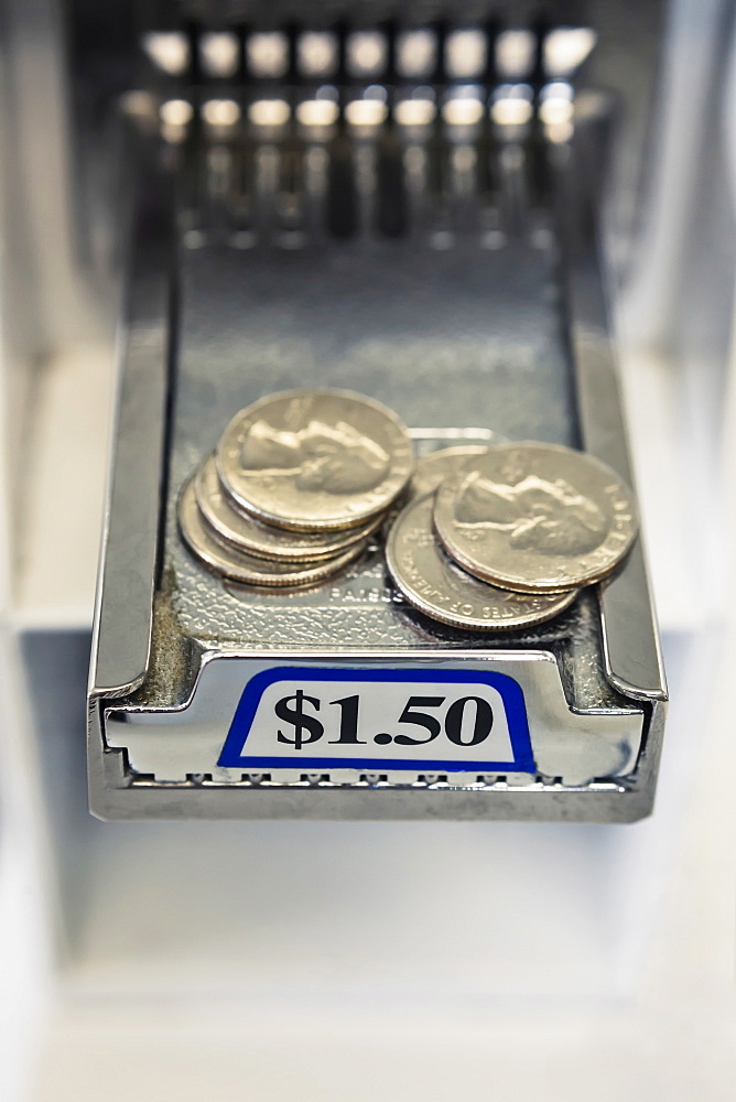 Quarters on sliding tray of coin operated washing machine