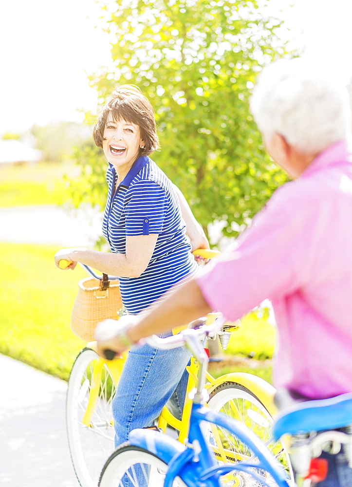 Portrait of woman looking over shoulder at senior man, while getting on bicycle and laughing, Jupiter, Florida