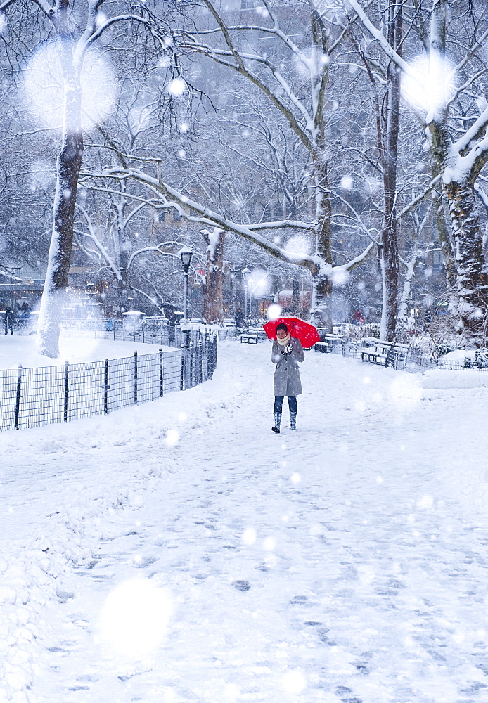 Woman walking with red umbrella on a snowy day