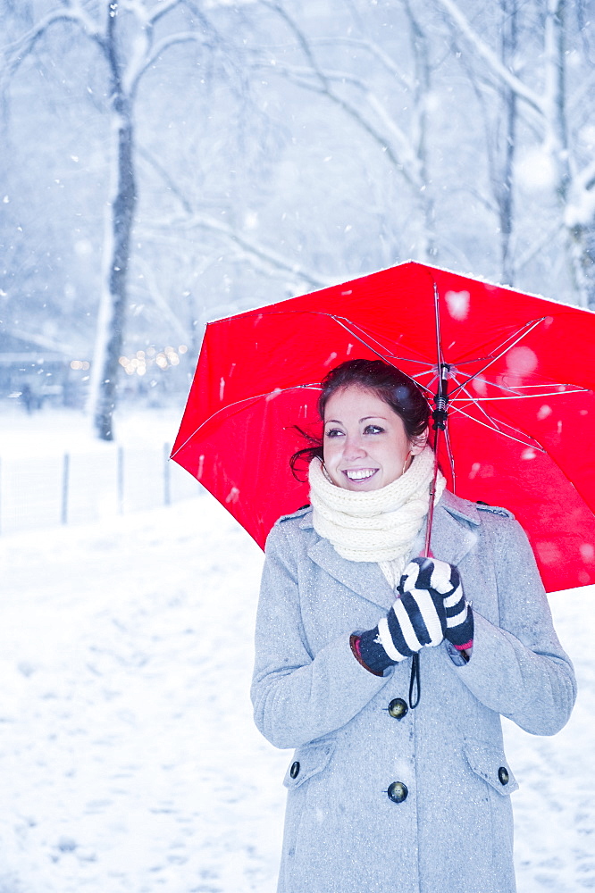 Woman walking with red umbrella on a snowy day