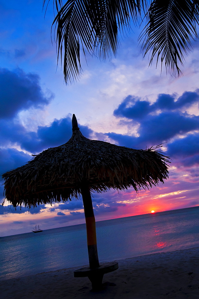 Aruba, silhouette of palapa on beach at sunset