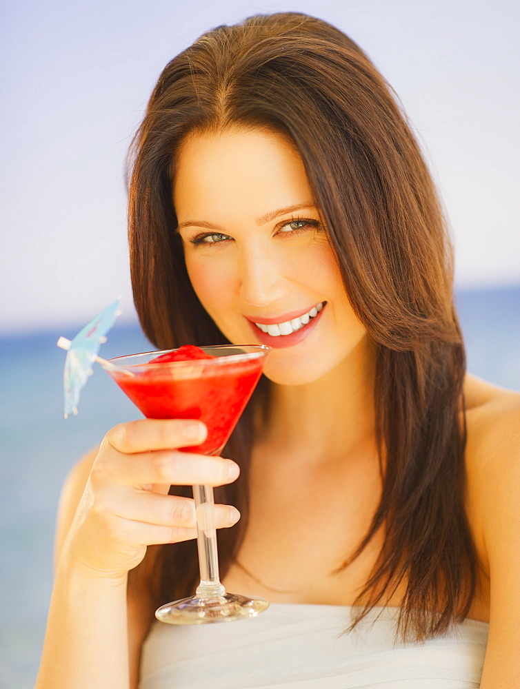 Portrait of young woman with cocktail, studio shot