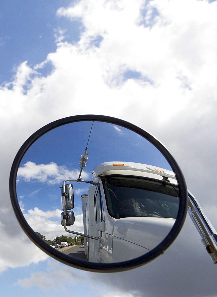 Reflection of semi-truck in side view mirror