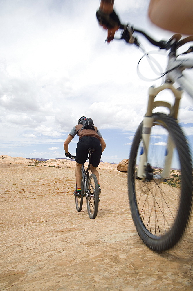 Low angle view of couple riding mountain bikes