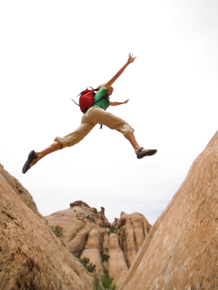 Woman jumping over rock formation