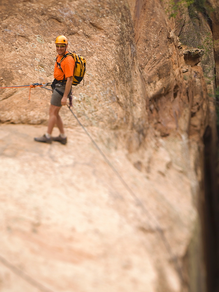 Man in rappelling gear at top of cliff