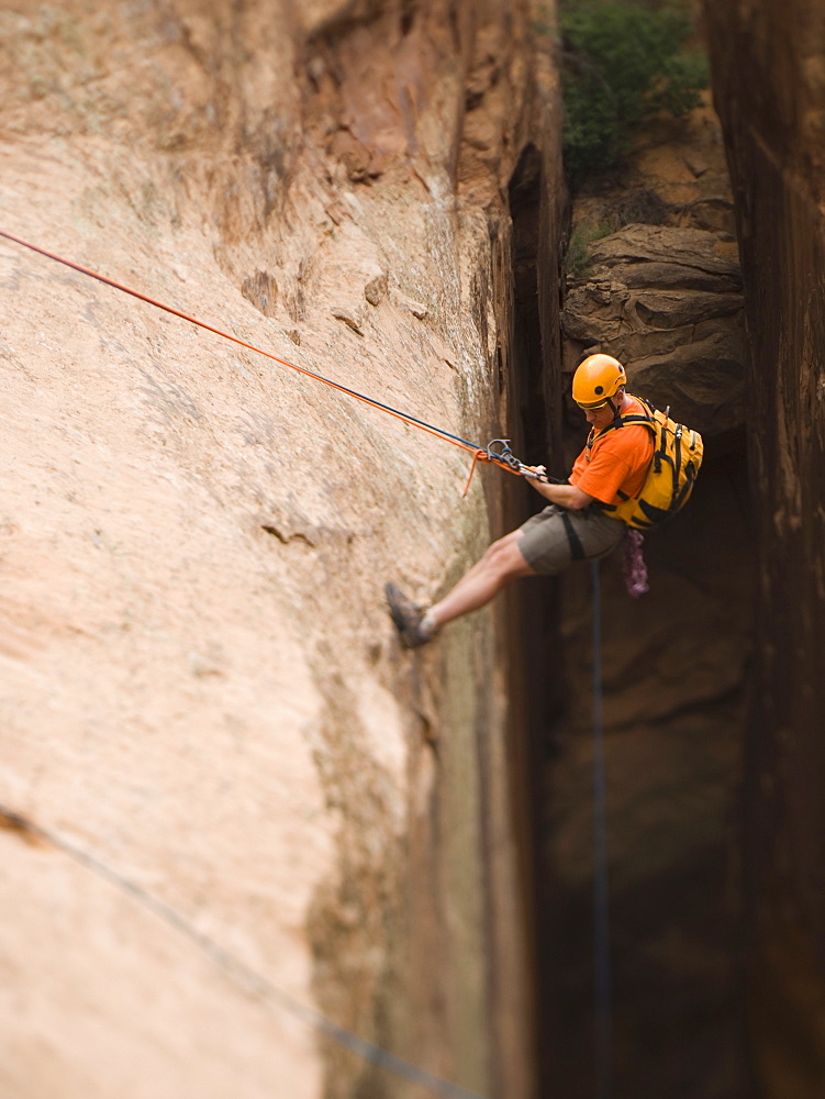 Man in rappelling gear at top of cliff