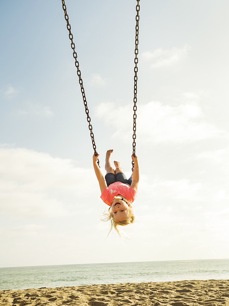 Girl (4-5) swinging on beach, San Clemente, California