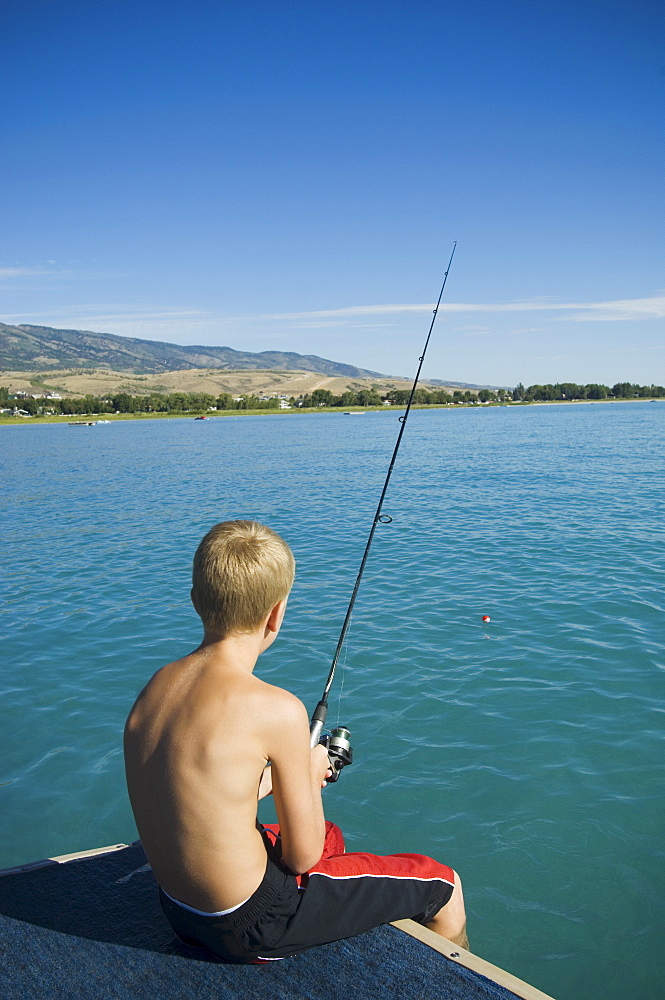 Boy fishing off dock in lake, Utah, United States