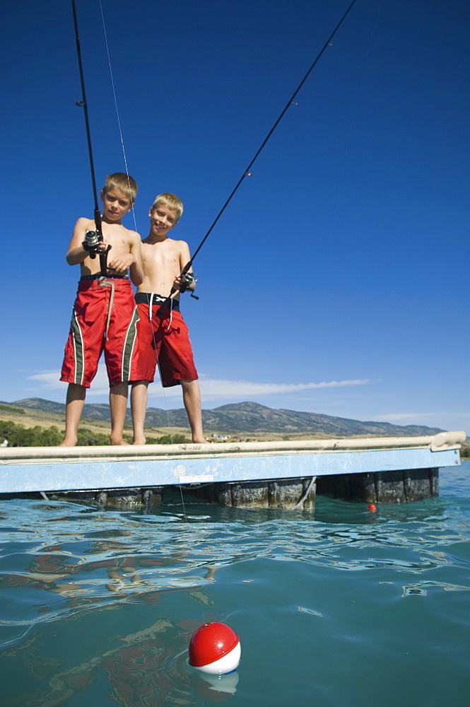 Brothers fishing off dock in lake, Utah, United States