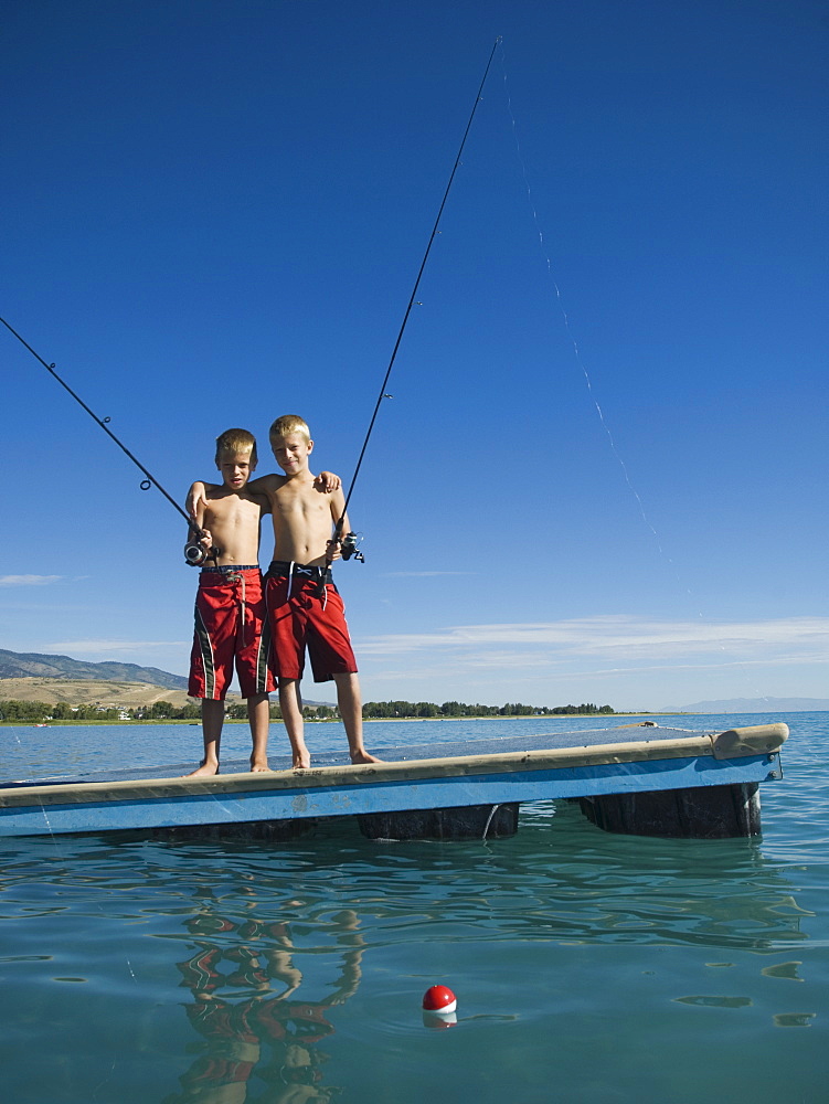 Brothers fishing off dock in lake, Utah, United States