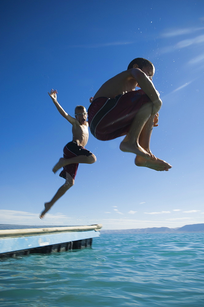 Brothers jumping off dock into lake, Utah, United States