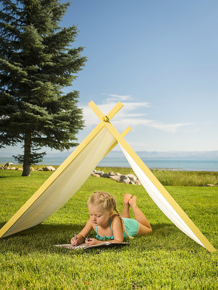 Girl (2-3) lying in tent, Garden City, Utah