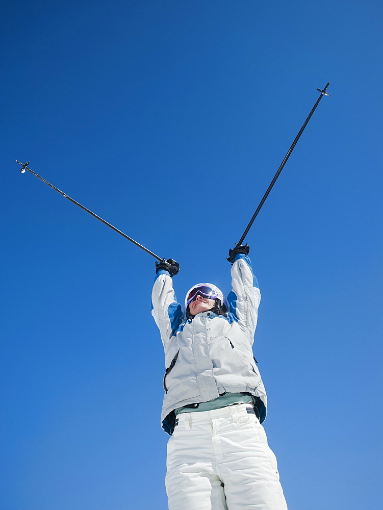 Woman holding ski poles over head