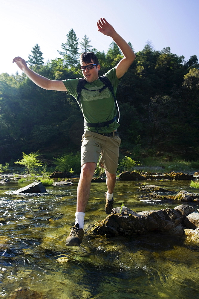 Man jumping across river on rocks