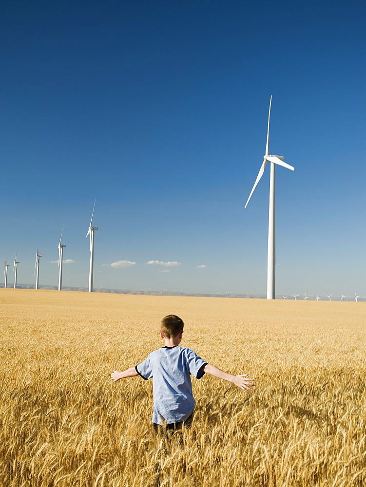 Boy running through field on wind farm