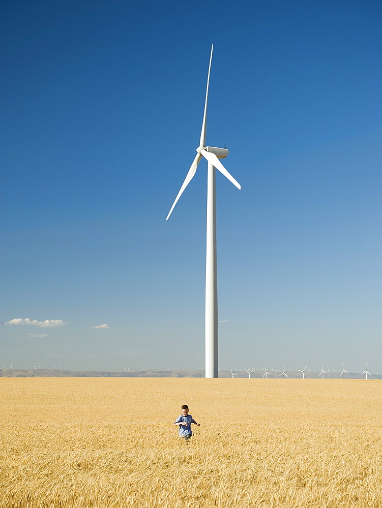 Boy running through field on wind farm